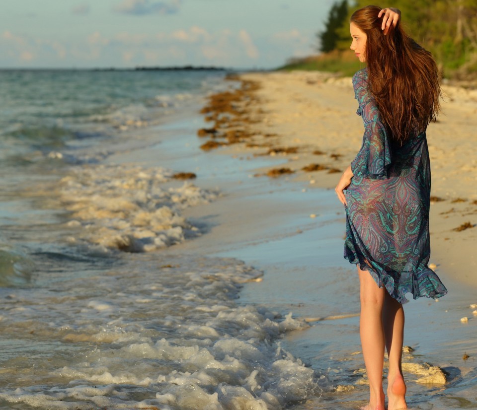 Молодая девушка снимает платье отдыхая на пляже