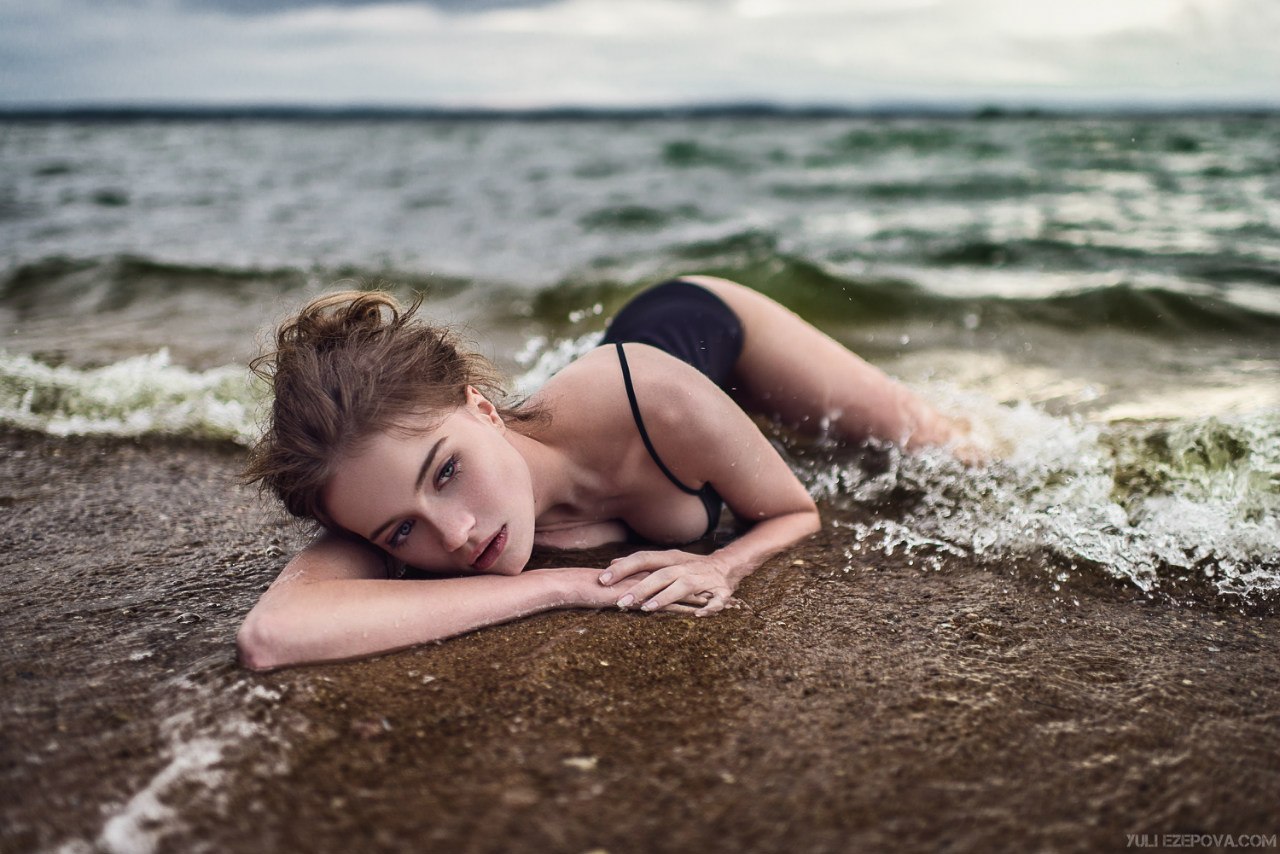 Обнаженная девушка в очках плещется в морской воде у каменных валунов порно фото