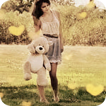 99px.ru аватар Девушка стоит на траве и держит в руке мишку teddy, вокруг блики-сердечки