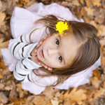 99px.ru аватар Девочка с желтым цветочком в волосах смотрит вверх, под ногами у неё осенние листья