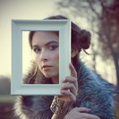 Аватар Девушка смотрит на нас через рамку, которую она держит в руках