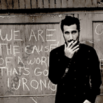 99px.ru аватар Музыкант и солист группы System of a Down Serj Tankian / Серж Танкян стоит среди надписей с дымящийся сигаретой