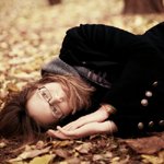 Аватар Девушка в черном пальто и очках лежит на осенних листьях