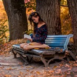 Аватар Девушка читает книгу, сидя на скамье в осеннем парке