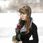 Аватар Девушка с розой в руках стоит на ветру на фоне заснеженного поля