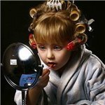 99px.ru аватар Маленькая девочка с бигудями на голове смотрит в зеркало и красит губы