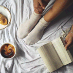 Аватар Девушка, сидя рядом с чашкой кофе с молоком, листает книгу