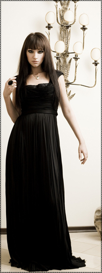 99px.ru аватар Певица Согдиана в чёрном платье стоит у стены на которой висит причудливый светильник