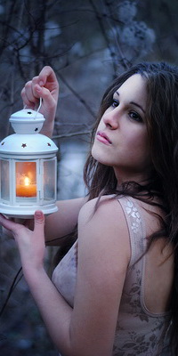 Аватар вконтакте Черноволосая девушка, стоящая на опушке леса, держащая в руке декоративный фонарь с зажженной свечой, автор Марина Остапенко