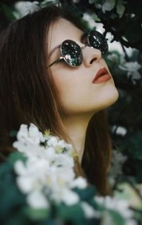 Аватар вконтакте Девушка в солнцезащитных очках стоит у цветущего куста