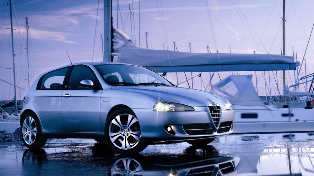 Обои для рабочего стола Серебристый автомобиль на причале в окружении яхт