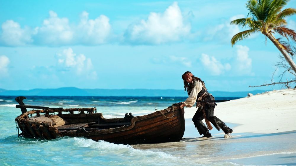 Обои для рабочего стола Джек Воробей выталкивает лодку в море из фильма «Пираты карибского моря»