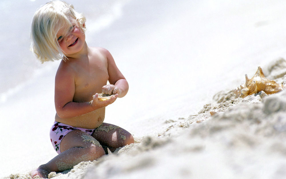 Обои для рабочего стола Мальчик играет с песком на пляже