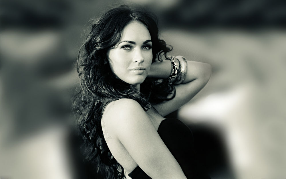 Обои для рабочего стола Меган Фокс / Megan Fox в черном платье на размытом фоне