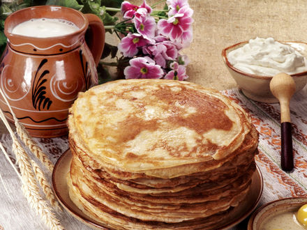 Обои на рабочий стол Русская кухня. Огромная стопка блинов, рядом молоко, яйца, сметана, стол украшен цветами