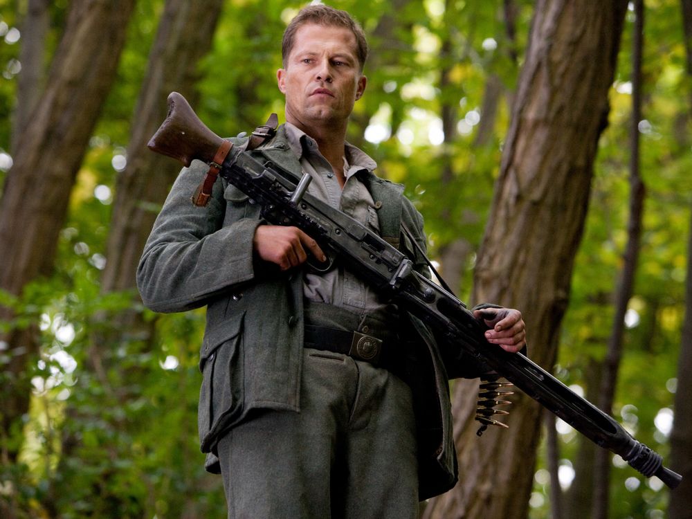 Обои для рабочего стола Немецкий актер Тиль Швайгер / Til Schweiger с винтовкой в лесу