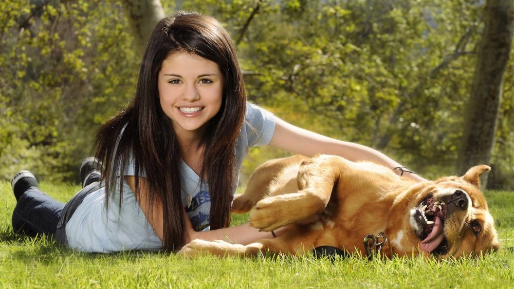 Обои для рабочего стола Селена Гомез/Selena Gomez  лежит на лужайке вместе с рыжей собакой