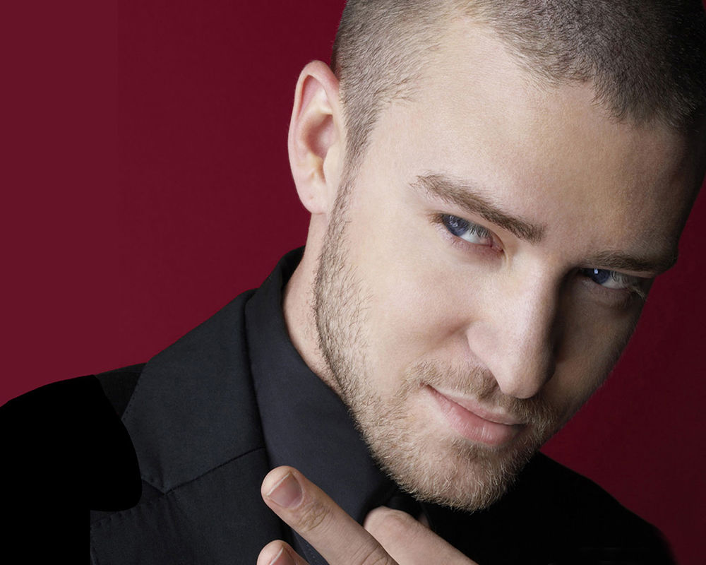 Обои для рабочего стола Певец Джастин Тимберлейк / Justin Timberlake в черном костюме и рубашке на бордовом фоне