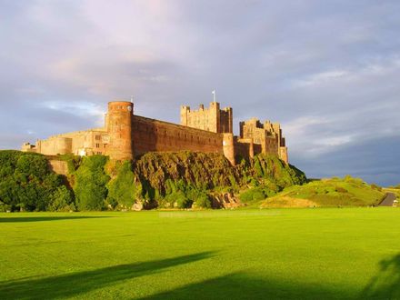 Обои на рабочий стол Замок Бамбург / Bamburgh Castle на горе, окруженный зеленым лугом, графство Нортумберленд / Northumberland, Великобритания