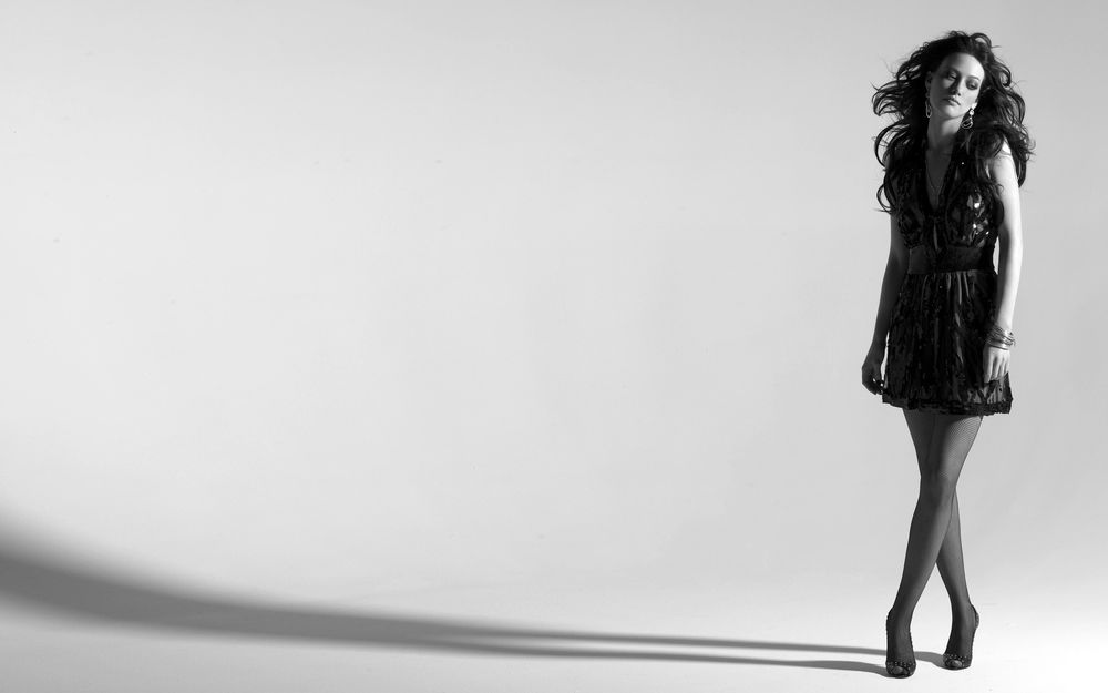 Обои для рабочего стола Актриса Хилари Дафф / Hilary Duff  грустная стоит у серой стены в черном платье