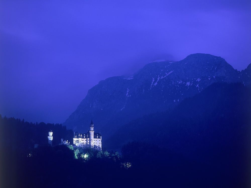 Обои для рабочего стола Замок Нойшванштайн / Schlob Neuschwanstein ночью среди гор и тумана, Фюссен, Германия