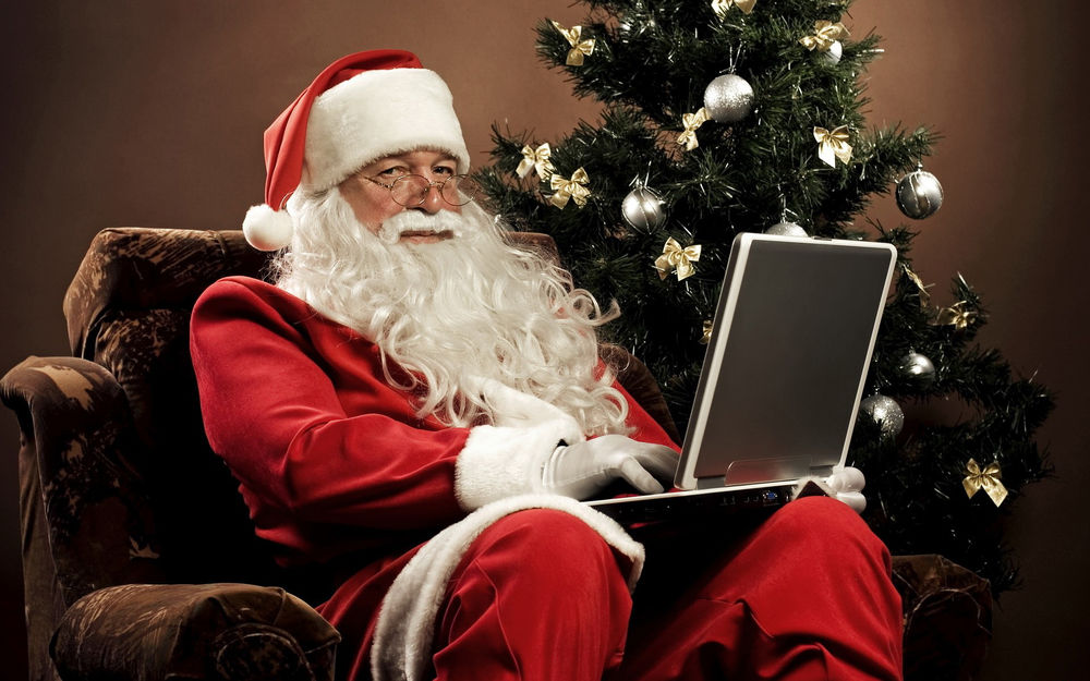 Обои для рабочего стола Санта Клаус сидит за ноутбуком