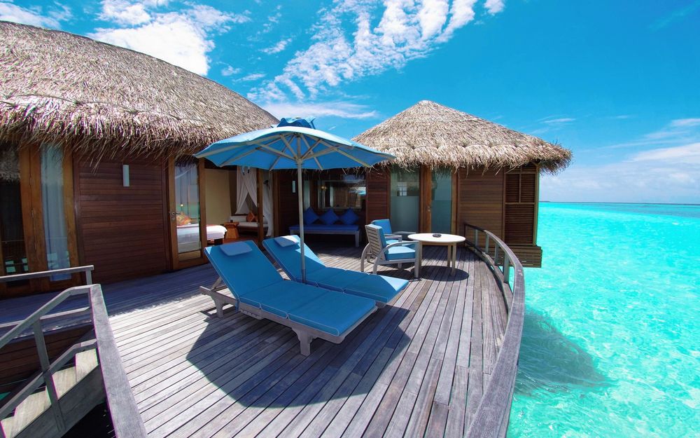 Обои для рабочего стола Тираса с шезлонгами и зонтом возле бунгало на одном из курортов Мальдивских островов