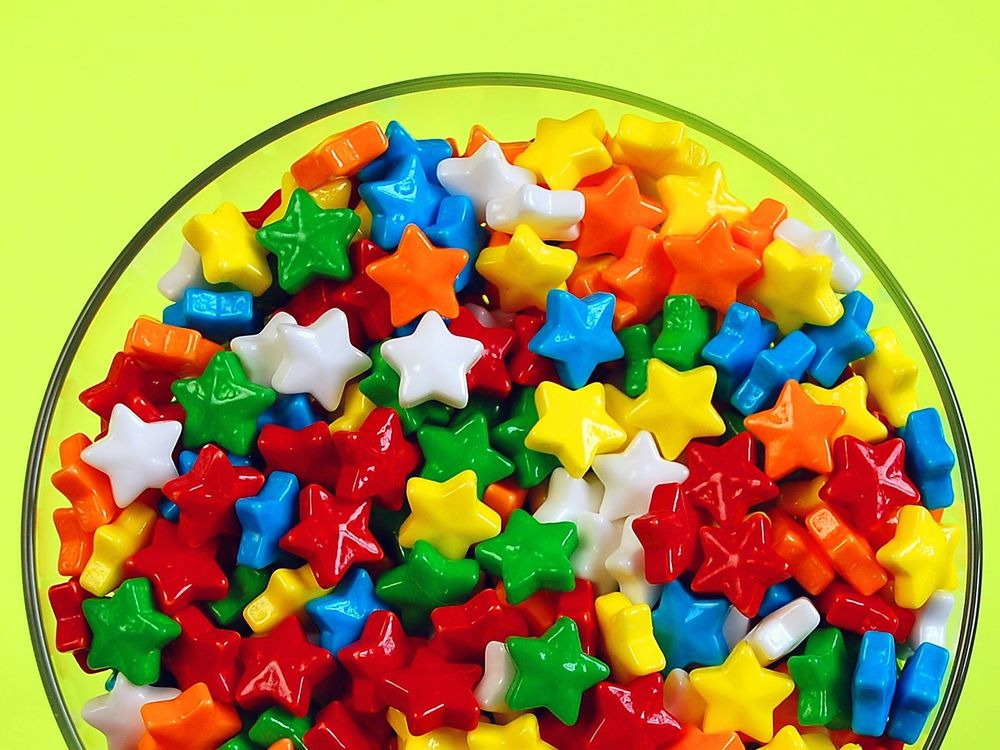 Обои для рабочего стола Множество разноцветных, маленьких конфет звёздочек в стеклянной тарелке