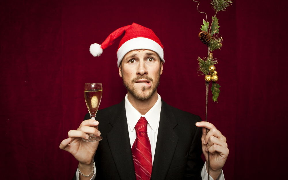 Обои для рабочего стола Корявый мужик в новогодней шапке с еловой веткой и бокалом шампанского