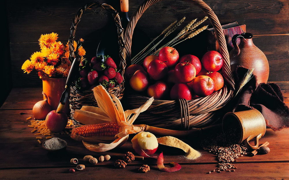 Обои для рабочего стола Корзина с красными яблоками стоит на столе возле букет цветов и разнообразных специй