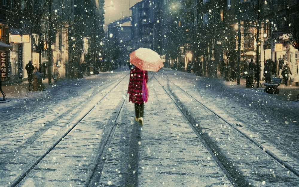 Обои для рабочего стола Девушка с зонтом идёт по дороге в снегопад