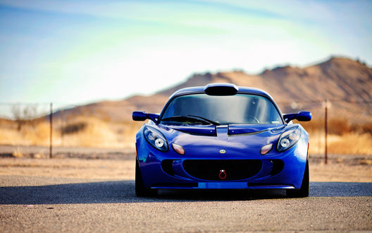 Обои на рабочий стол Автомобиль Lotus Elise синего цвета стоит на дороге