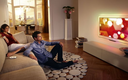 Обои на рабочий стол Парень и девушка дома смотрят большой телевизор Philips
