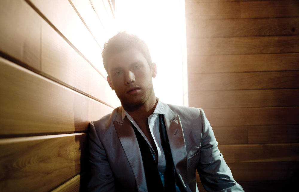 Обои для рабочего стола Красавец Джон Маклафлин / Jon McLaughlin в сером костюме в лучах солнечного света, струящегося за его спиной