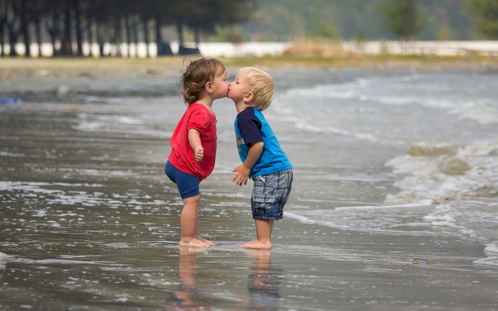 Девочка и мальчик целуются с мороженым в руках - Фото