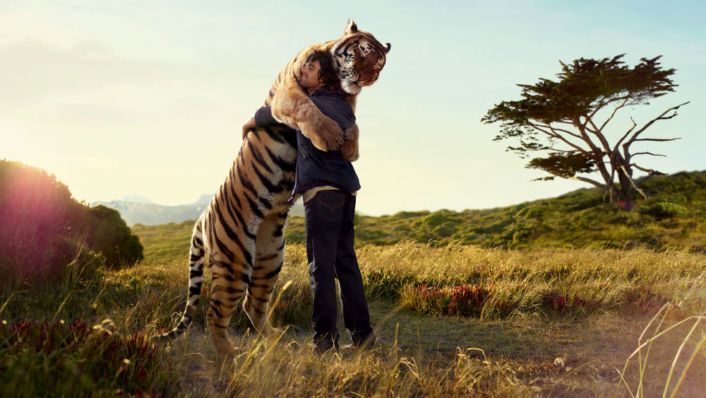 Обои для рабочего стола Глубокая и искренняя любовь человека и животного - парень обнимается с огромным тигром посреди саванны
