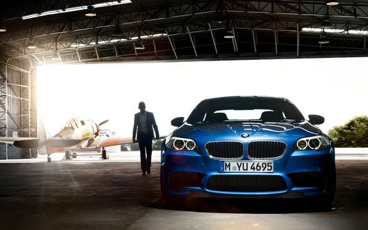 Обои на рабочий стол Парень идет от самолета к синему БМВ / BMW