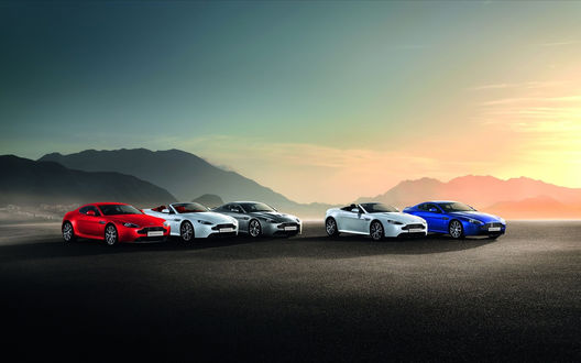 Обои на рабочий стол Пять машин марки Aston Martin / Астон-Мартин красного, белого, серого и синего цветов, стоят на дороге