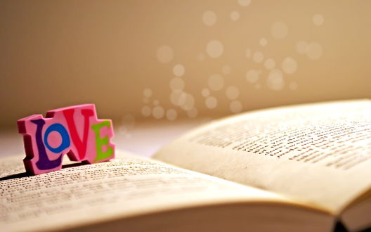 Обои на рабочий стол Резинка в форме слова *Love / Любовь* на странице книги