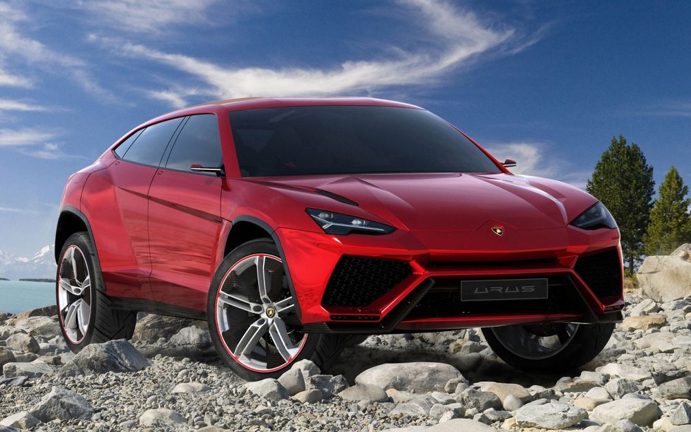 Обои для рабочего стола Красный Lamborghini / Ламборгини стоит на камнях на фоне деревьев и неба