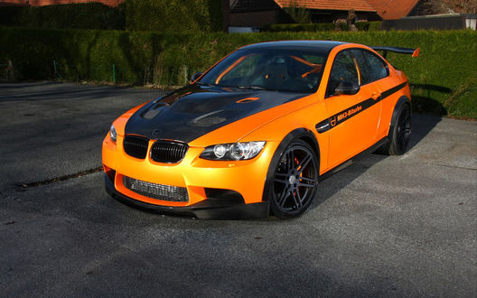 Обои на рабочий стол Оранжево-черный BMW m3 manhart v8r biturbo / БМВ м3 манхарт в8р битурбо стоит на дороге