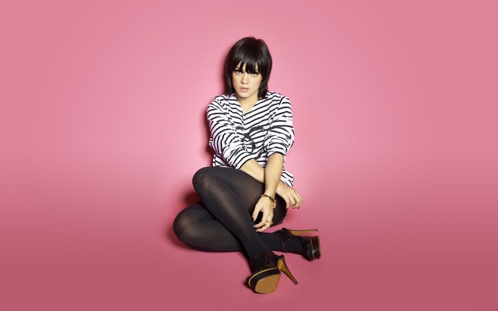 Обои для рабочего стола Lily Allen / Лилу Аллен сидит на розовом фоне