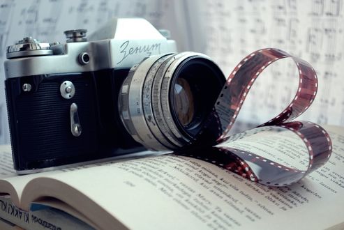 Обои на рабочий стол Фотоаппарат «Зенит» лежит на раскрытой книге, нотах и пленке свернутой в форме сердечка
