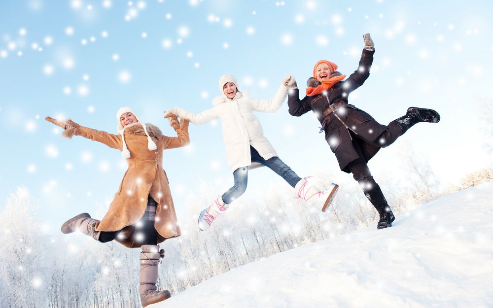 Обои для рабочего стола Три девушки радуются падающему снегу, высоко прыгают и смеются