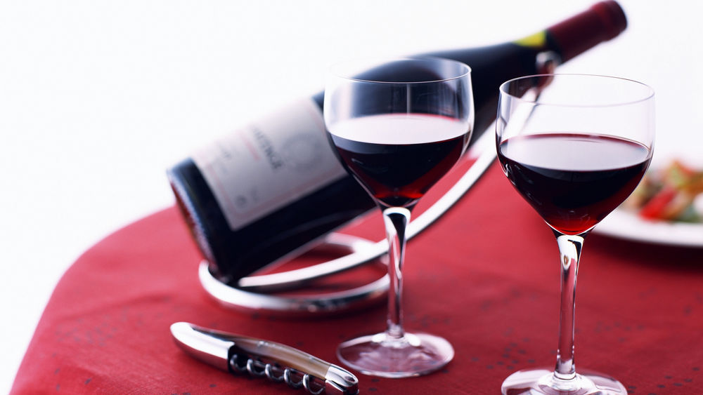 Обои для рабочего стола Бутылка красного вина и бокал с налитым вином на красной скатерти