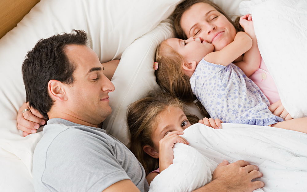 Обои Семья отдыхает на постели, две забавные дочки, отец и мама ...