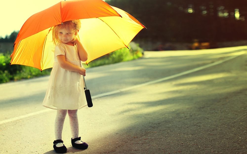 Обои для рабочего стола Маленькая девочка под зонтиком стоит на дороге