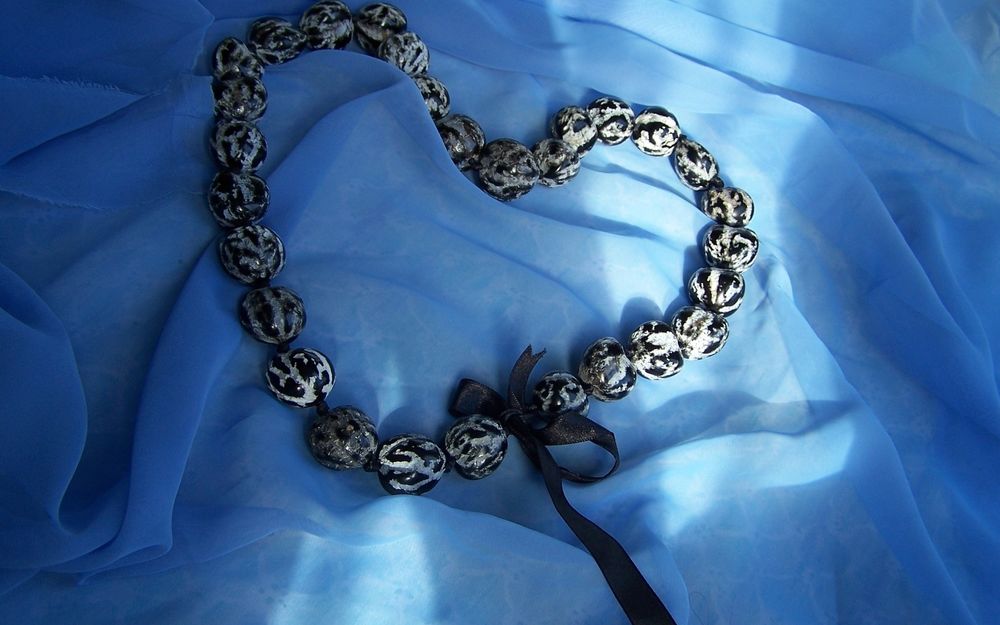 Обои для рабочего стола Чёрно-белое ожерелье на синей ткани, сложенное в виде сердца
