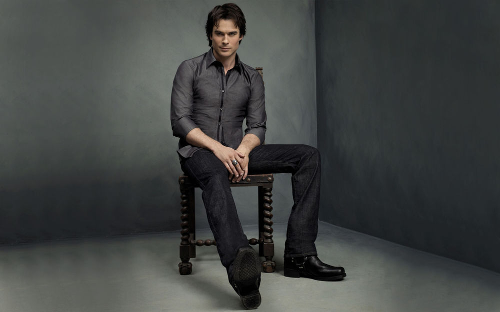 Обои для рабочего стола Ian Somerhalder / Иэн Сомерхолдер сидит на деревянном старинном стуле в серой рубашке и джинсах с перстнем на руке