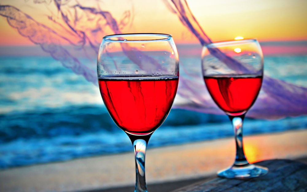 Обои для рабочего стола Два бокала с красным вином на фоне вечернего моря